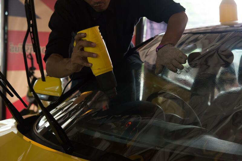 Worker fitting new tint to the window of a car